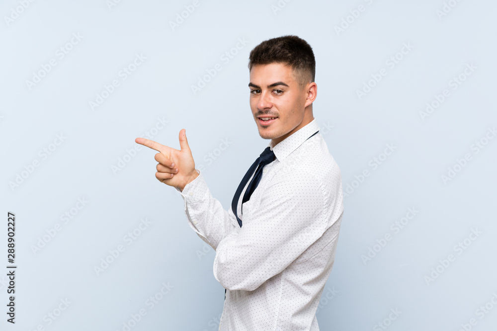 Handsome businessman over isolated blue background pointing finger to the side Handsome businessman over isolated blue background pointing finger to the side