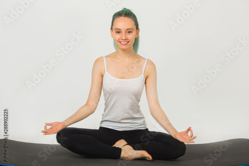 beautiful young woman doing gymnastics in yoga pose on a white background