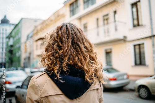 Woman with curly hair in a beige coat