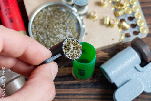 reloading process shotgun shells with special reload equipment. Powder, bullets, fraction, shells, buckshot on the wooden background photo