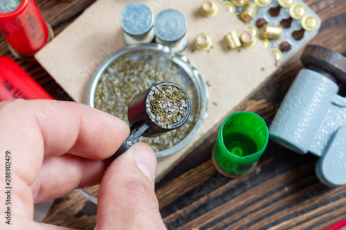 reloading process shotgun shells with special reload equipment. Powder, bullets, fraction, shells, buckshot on the wooden background photo