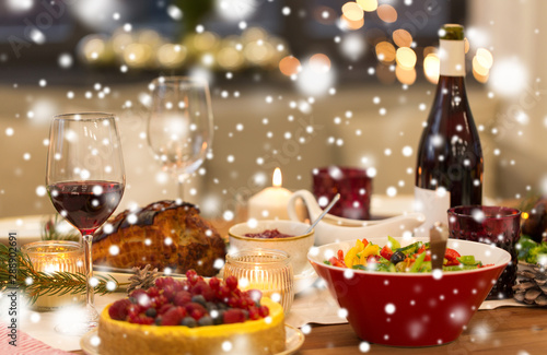 christmas dinner and eating concept - food and drinks on table at home over snow