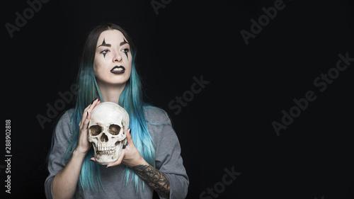 Bild auf Leinwand Attractive girl with harlequin makeup holding skull