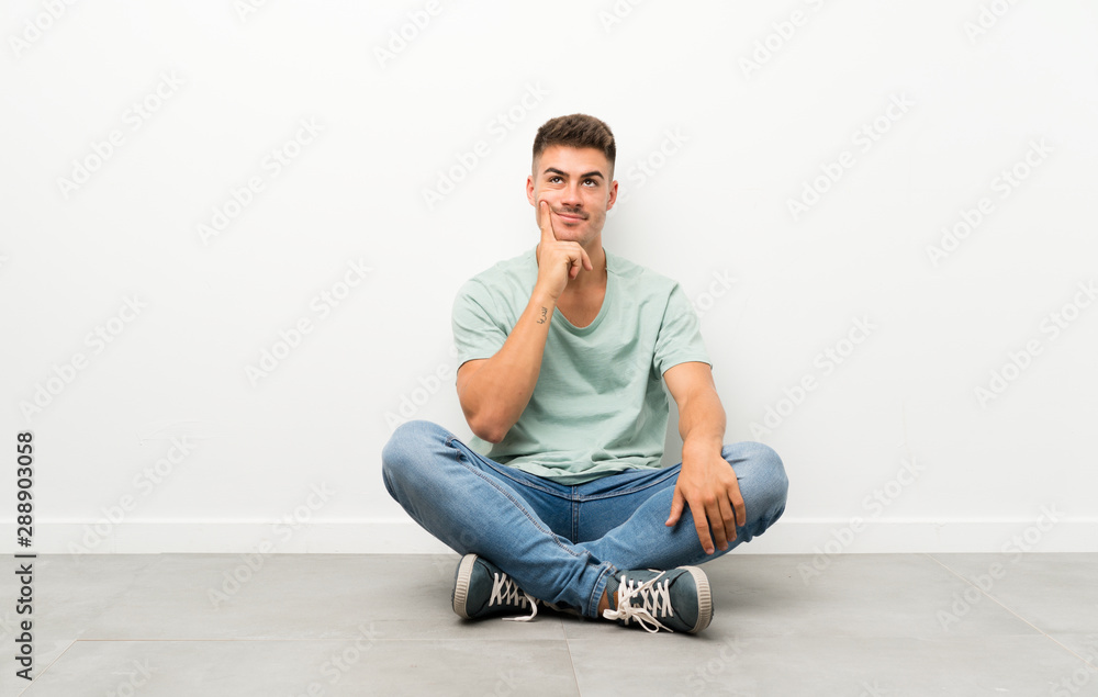 Young handsome man sitting on the floor thinking an idea Young handsome man sitting on the floor thinking an idea