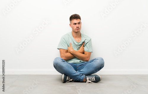 Young handsome man sitting on the floor thinking an idea