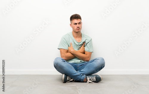 Young handsome man sitting on the floor thinking an idea © luismolinero