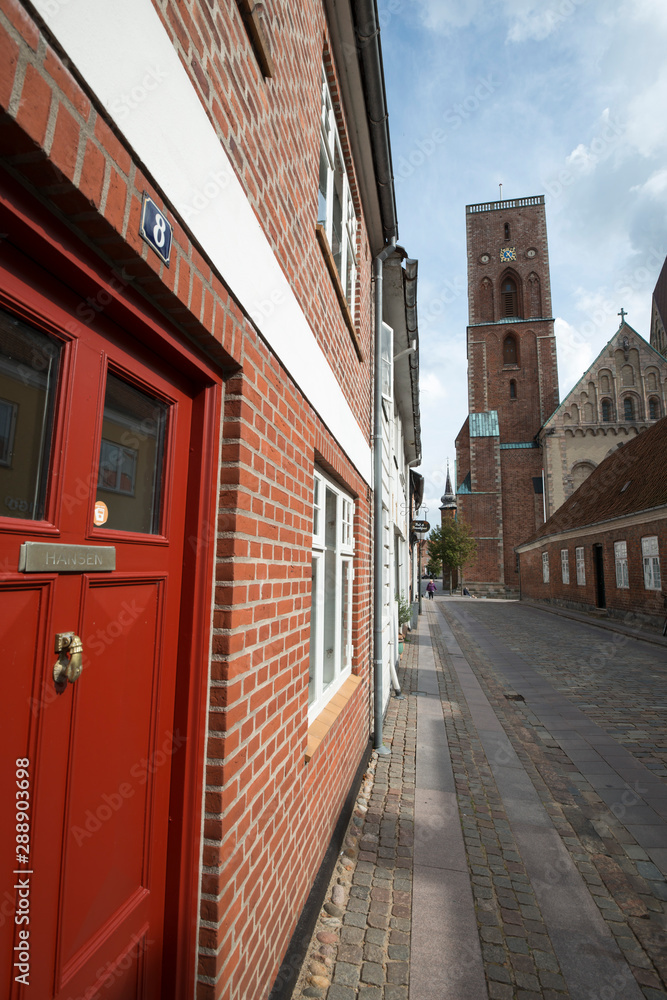 Rote Haustür in Straße vor Kirchturm