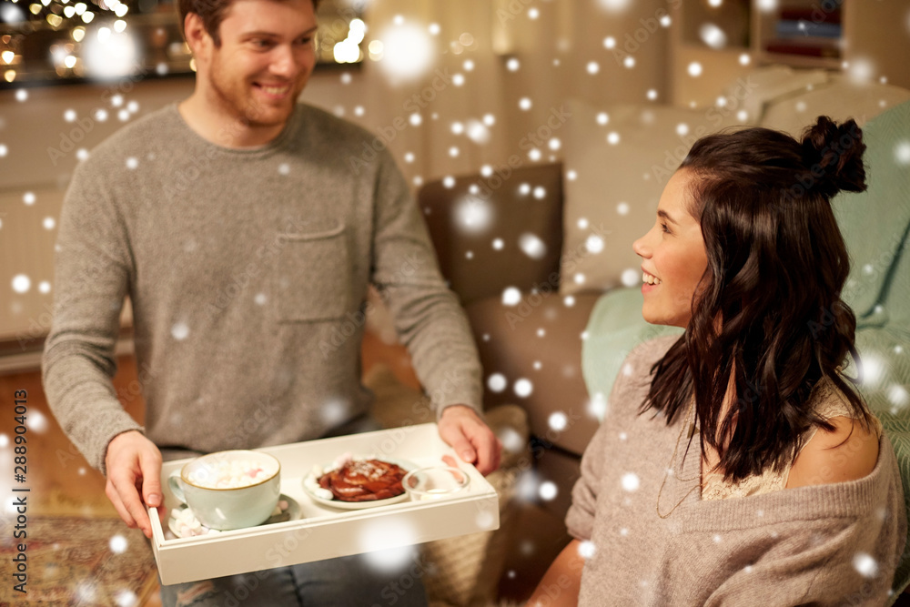 leisure, christmas and people concept - happy couple with food on tray at home over snow