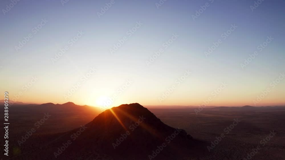 Sunrise peeking over Mojave Desert horizon with silhouette mountain, AERIAL Sunrise peeking over Mojave Desert horizon with silhouette mountain, AERIAL