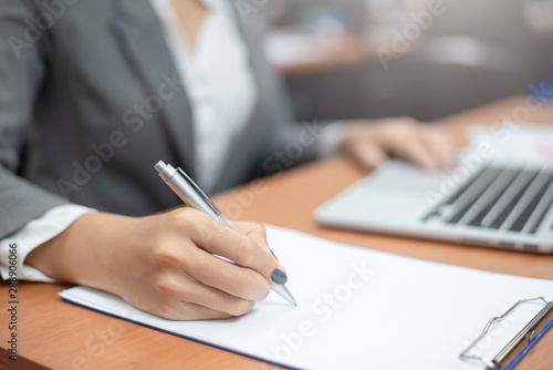 Close-up of female hands. Business woman writing something sitting at her office. Checking documents