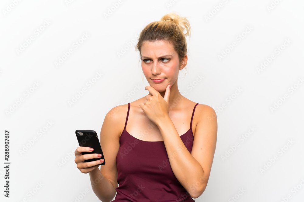 Young blonde woman using mobile phone thinking an idea Young blonde woman using mobile phone thinking an idea
