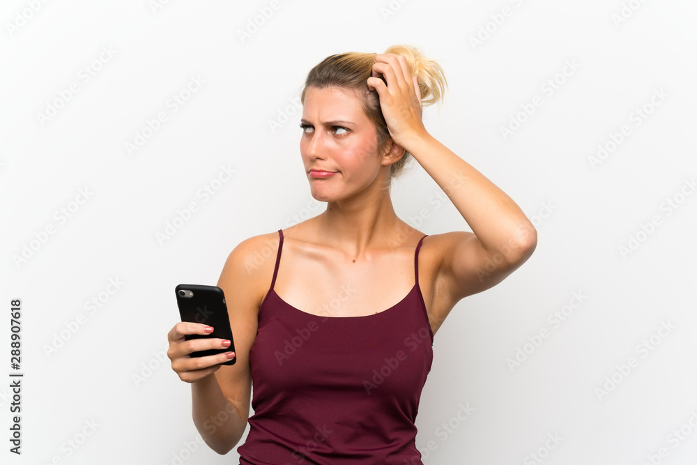 Young blonde woman using mobile phone having doubts and with confuse face expression Young blonde woman using mobile phone having doubts and with confuse face expression