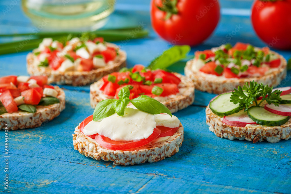 homemade sandwiches rice cakes with mozzarella tomatoes basil and chopped vegetables on blue wooden table close up homemade sandwiches rice cakes with mozzarella tomatoes basil and chopped vegetables on blue wooden table close up