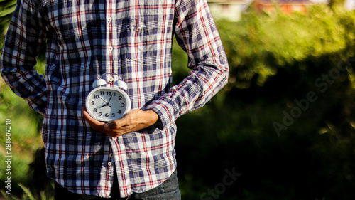 An alarm clock in the hand of a man