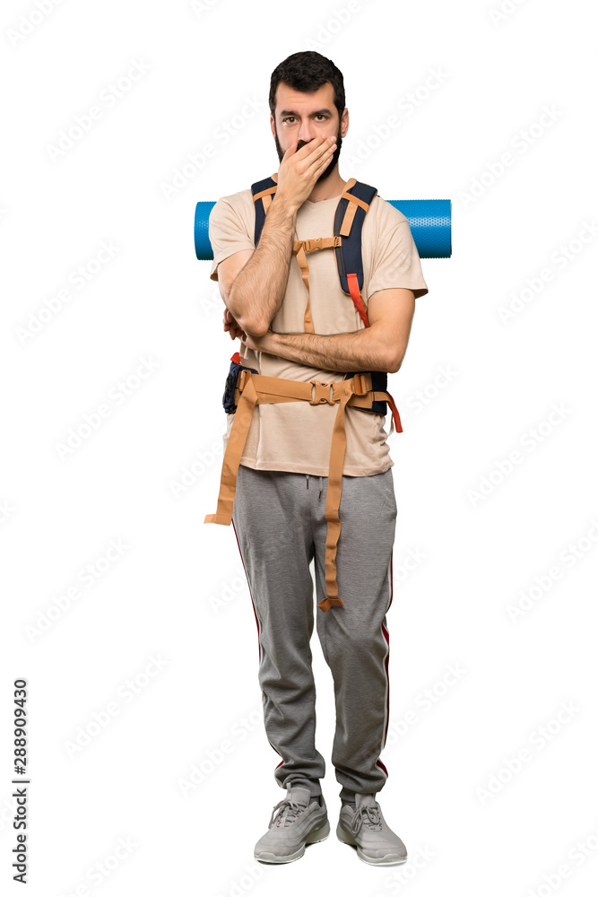 Hiker man covering mouth with hands over isolated white background Hiker man covering mouth with hands over isolated white background