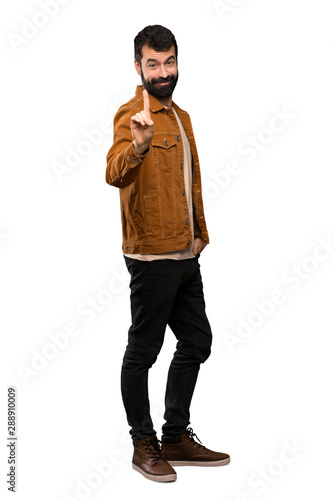 Handsome man with beard showing and lifting a finger over isolated white background © luismolinero