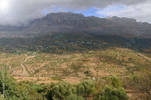 Beautiful valley with tree, shrubs and bushes and a little mountain village in front of the foggy Rif / Riff mountains in the North of Morocco, Africa