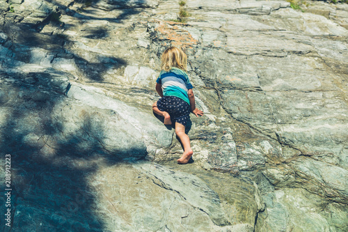 Cuadro en lienzo Little toddler climbing on rocks