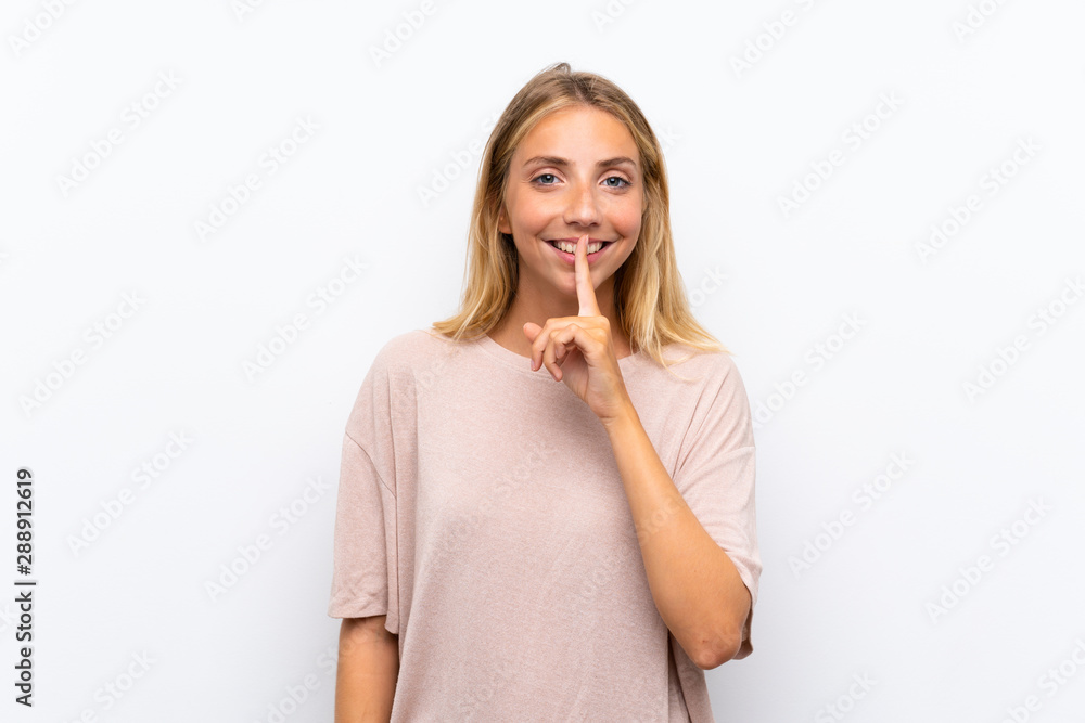 Blonde young woman over isolated white background doing silence gesture Blonde young woman over isolated white background doing silence gesture