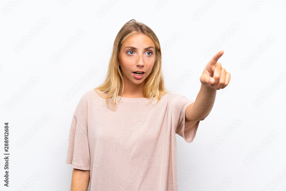 Fototapeta premium Blonde young woman over isolated white background pointing away