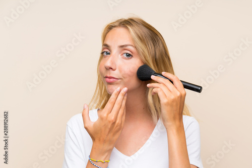 Young blonde woman with makeup brush.