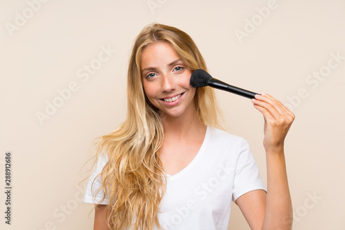 Happy Young blonde woman with makeup brush.