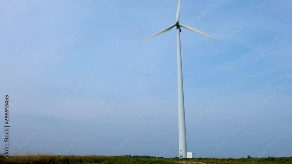 rotating blades of a windmill propeller on blue sky background. Wind power generation. Pure green energy. rotating blades of a windmill propeller on blue sky background. Wind power generation. Pure green energy.