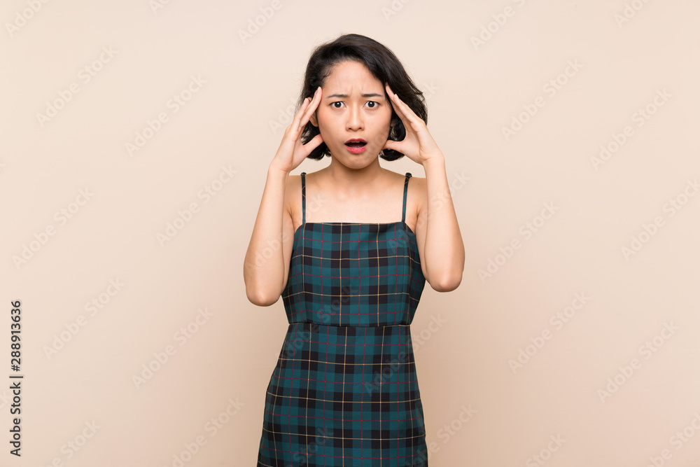 Asian young woman over isolated yellow wall with surprise expression Asian young woman over isolated yellow wall with surprise expression