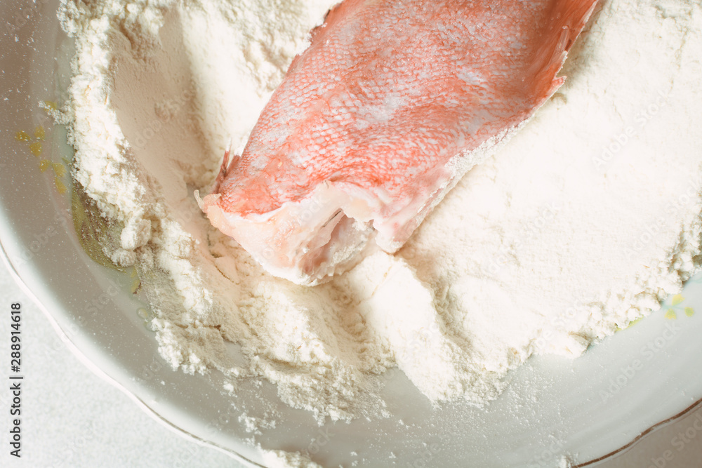 Fototapeta premium Fresh sea bass rolled in white flour for frying in pan.