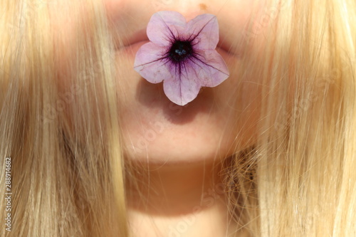 blondes Mädchen mit Blume im Mund