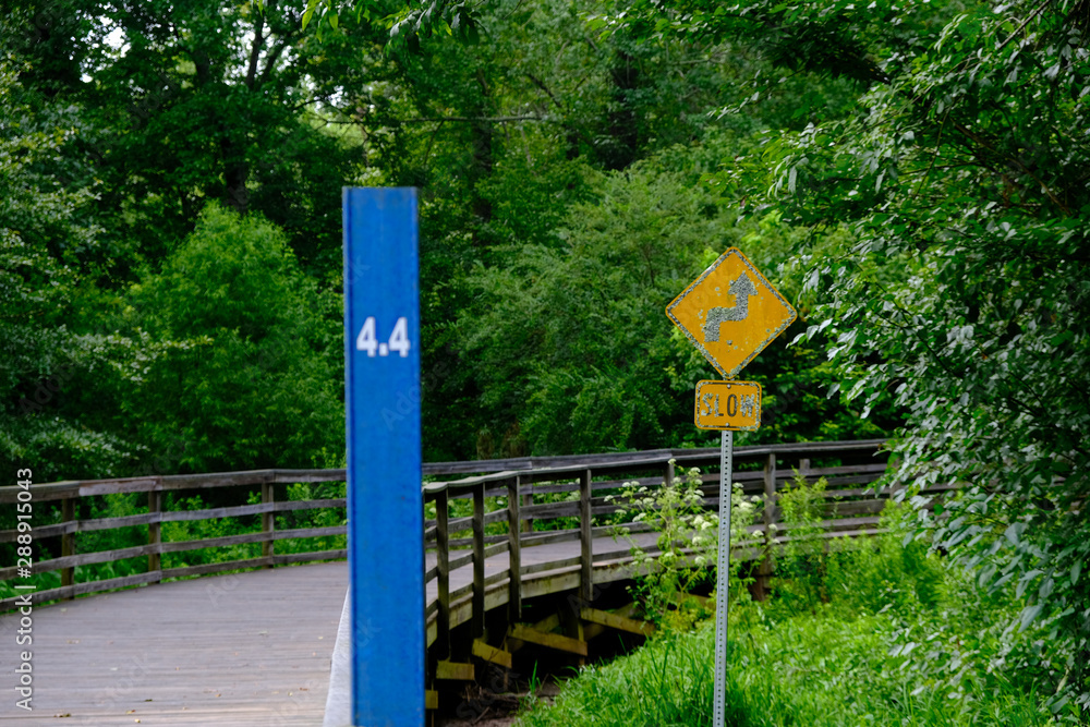 A mile marker and curve sign on a woodland fitness trail