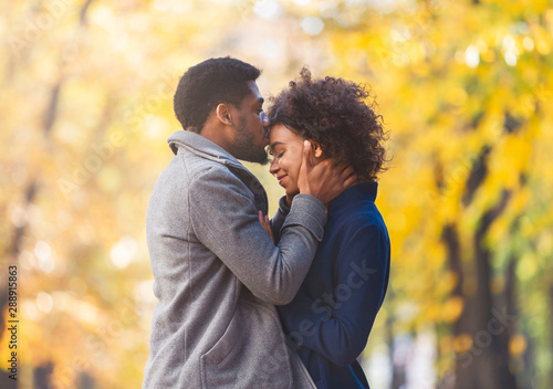 Loving black guy tenderly kissing his woman forehead