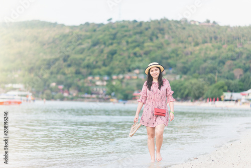 Beautiful woman wearing a hat Happy to stroll by the sea Listening to the sea, surfing the wind In the evening, the sun is falling by the sea in Thailand. The concept of resting during the holidays