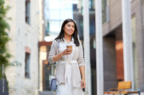 lifestyle and people concept - happy smiling young asian woman with takeaway coffee cup walking along city street