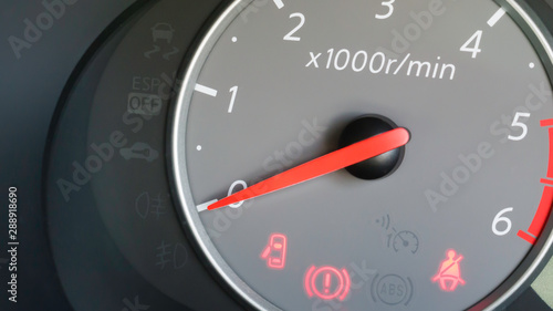 Grey rpm counter at zero revs, showing door open, handbrake on and fasten seatbelt indicators being illuminated.