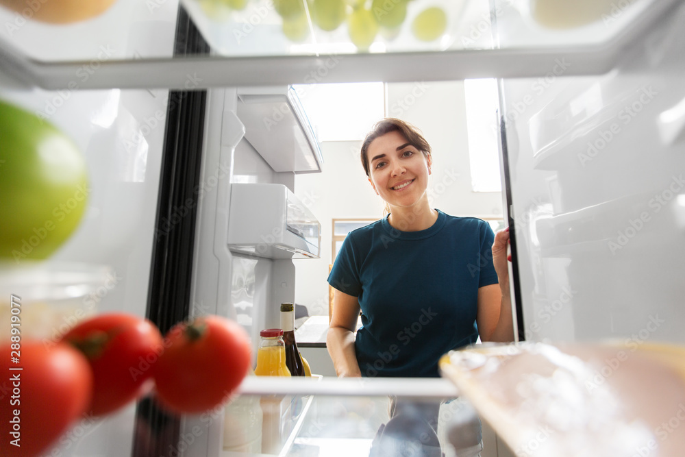 healthy eating, food and diet concept - happy woman at open fridge at home kitchen healthy eating, food and diet concept - happy woman at open fridge at home kitchen