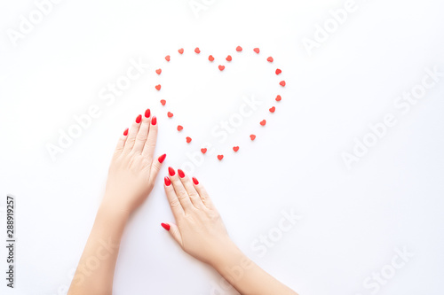 Hands of a beautiful well-groomed woman with red nails on a white background. Nail polishing in white.