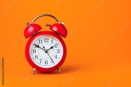Red alarm clock on orange background