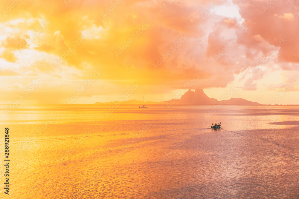 Tahiti sunset idyllic reflections of the sun setting over the ocean with yellow glowing colors in the sky and pink clouds in French Polynesia. Bora Bora island far away. Tahiti sunset idyllic reflections of the sun setting over the ocean with yellow glowing colors in the sky and pink clouds in French Polynesia. Bora Bora island far away.