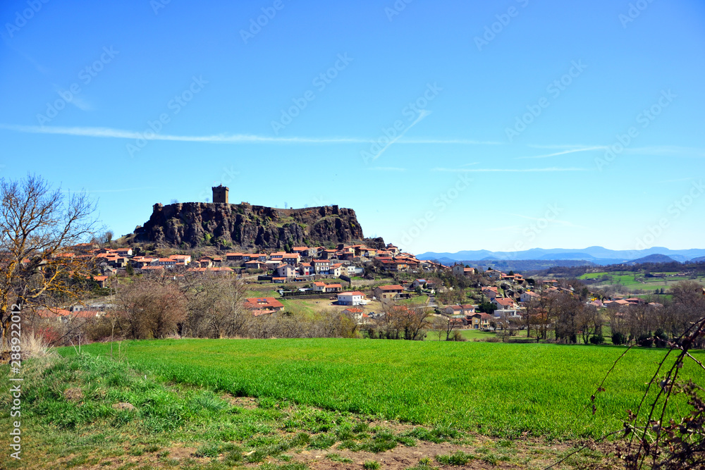 Polignac, France - March 30th 2019 : Focus on the fortified casltle of Polignac, built in the XII th century, from a green grass field.