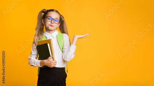 Dissatisfied First-Grade School Girl Shrugging Shoulders In Studio