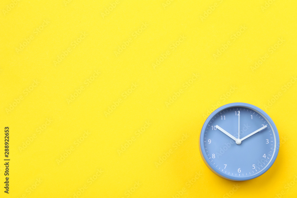 Blue round clock on yellow background - obrazy, fototapety, plakaty 