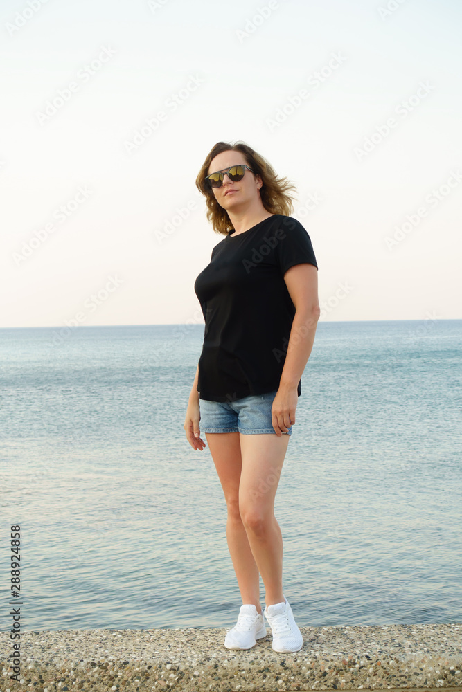 young woman in shorts posing on the seashore