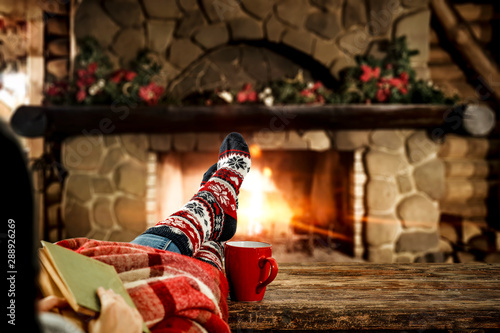 Woman legs with christmas socks and fireplace in home interior 