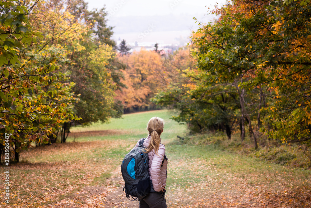 Fototapeta premium Hiking woman with backpack enjoying trek in autumn forest