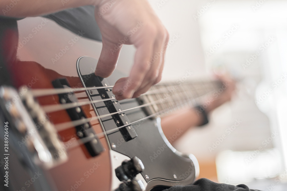 A man plays a bass guitar close-up. Toned photo. - obrazy, fototapety, plakaty 