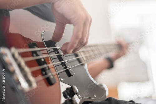 A man plays a bass guitar close-up. Toned photo. photo