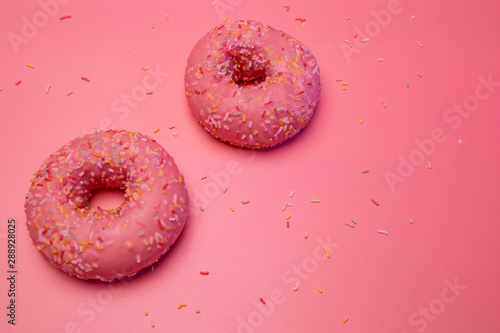 Two isolated glazed donuts with colorful candy shavings.