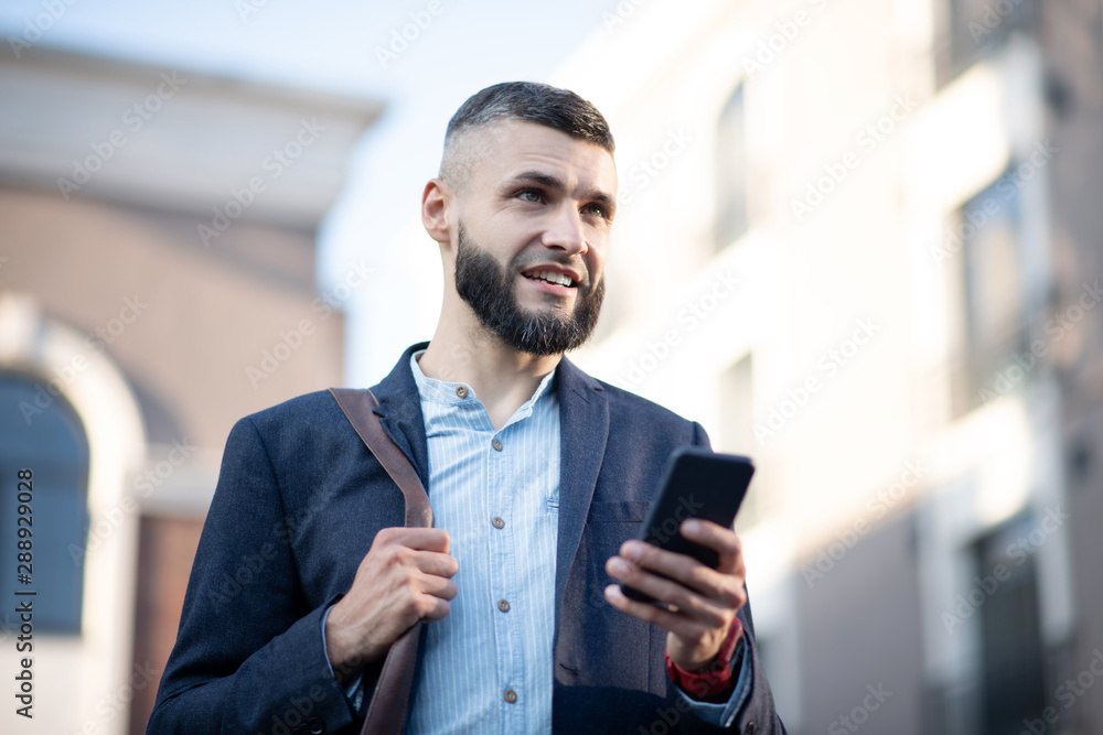Businessman holding smartphone while standing outside Businessman holding smartphone while standing outside