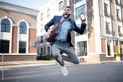 Handsome man jumping after reading message from company